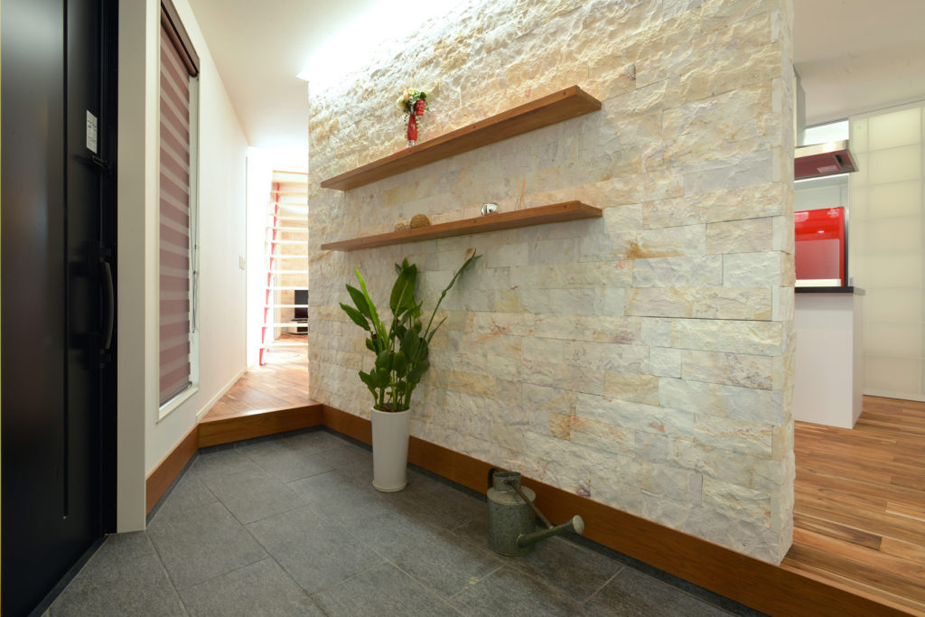 天然石調の壁がおしゃれで2方向の動線が便利な玄関